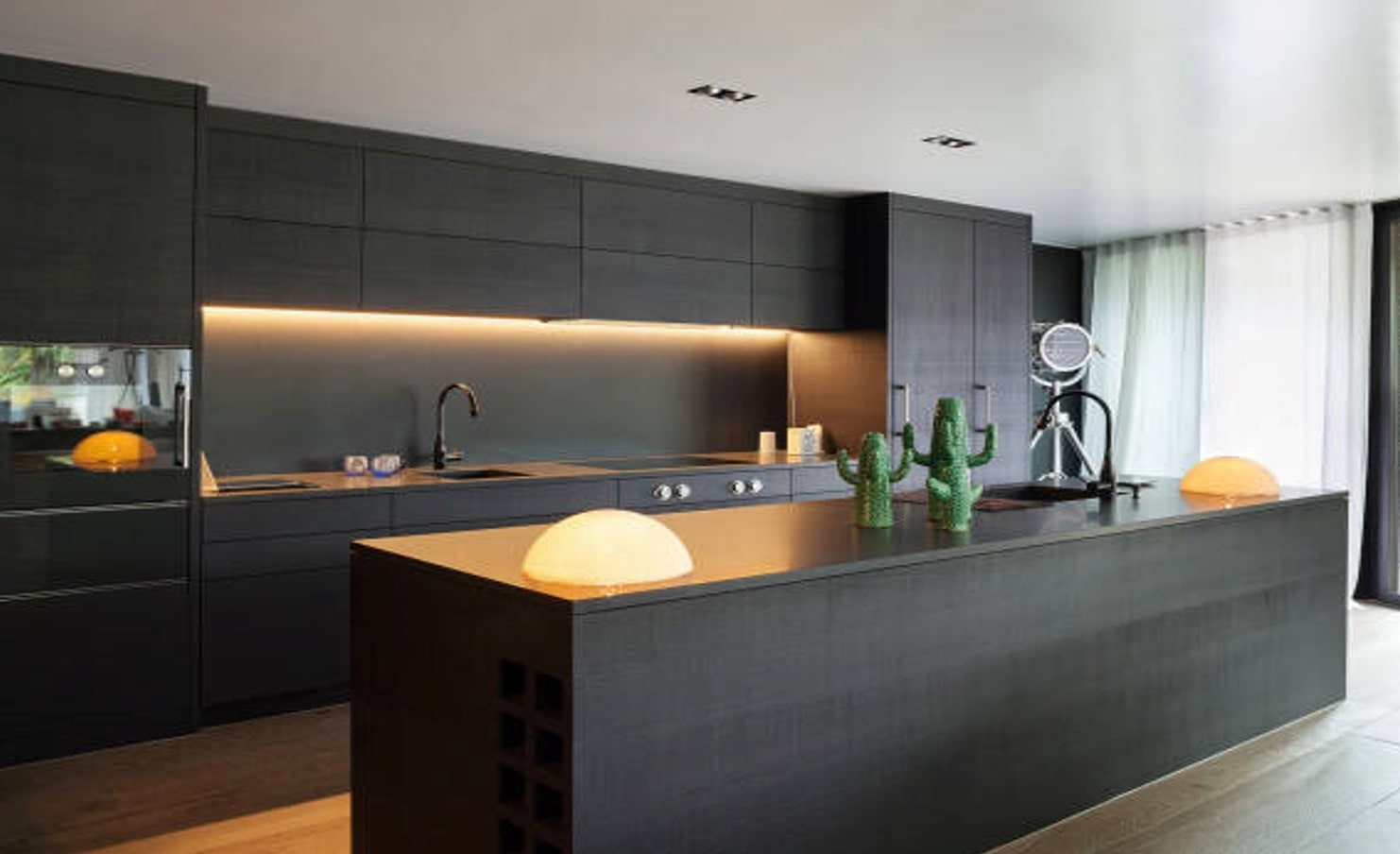 Kitchen with black cupboards and countertops lit with warm LED lighting